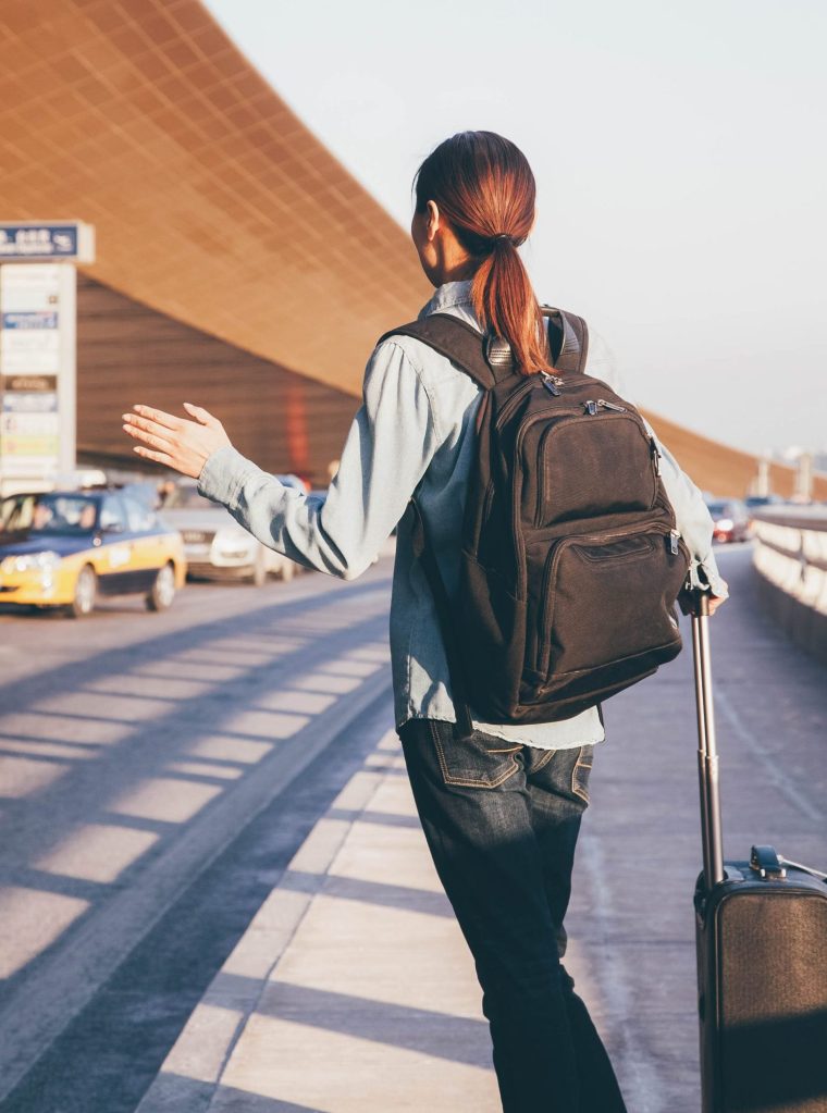 Young traveler hailing a taxi at airport
